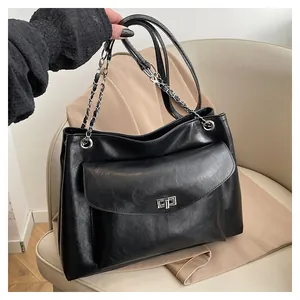 Detail of black tote bag featuring soft leather texture and silver chain strap design