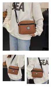 Detail of brown nylon crossbody bag featuring round SPORT logo and adjustable black strap