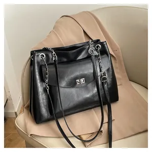 Close-up of black leather tote bag with silver chain strap and square turn-lock closure