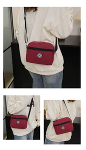 Close-up of wine red nylon crossbody bag with sport star embroidery and adjustable strap