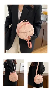 Detailed view of pink round quilted bag featuring embroidered brown bows and adjustable strap