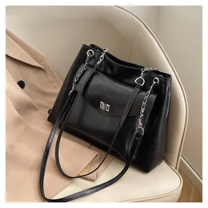 Close-up of black PU leather tote bag with silver metal twist lock and chain strap details