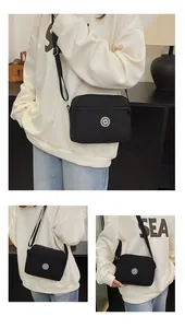 Close-up of black nylon crossbody bag with adjustable strap and circular sport logo