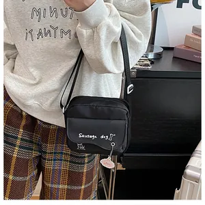 Détail du sac bandoulière en nylon noir avec motif teckel et breloque nuage rose