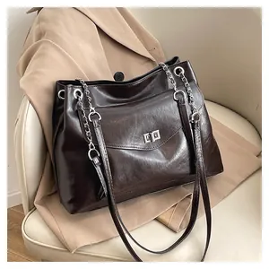 Detail of dark brown faux leather tote bag with silver chain strap and metal swivel lock