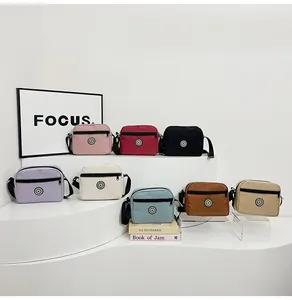 Multiple colors of lightweight nylon crossbody bags displayed on minimalist white stairs
