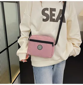 Pink nylon crossbody bag with zipper compartment and sport logo worn by a model