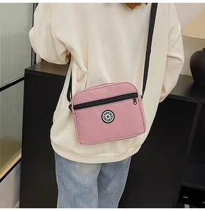 Pink nylon crossbody bag with black sport logo shown from back on a person