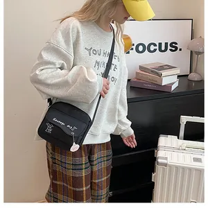 Détail d'un sac bandoulière noir en toile avec motif teckel porté par un mannequin féminin