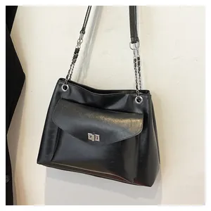 Detail of black PU leather tote bag with silver metal twist lock and chain strap links