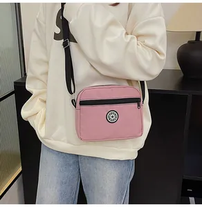 Close-up of pink Oxford cloth crossbody bag with adjustable strap worn by model