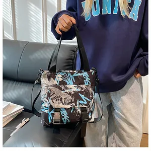 Detail of nylon messenger bag featuring blue and white graffiti print and buckle closure