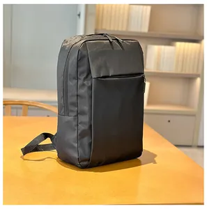 Minimalist black business laptop backpack standing on a wooden desk in a cozy office setting