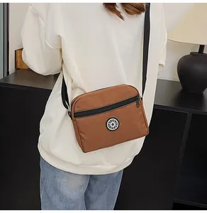 Detailed close-up of brown nylon crossbody bag with adjustable strap and sport logo