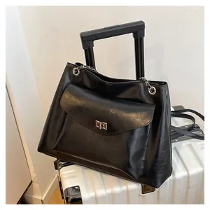Detail of black matte leather tote with silver metal turn-lock and chain strap