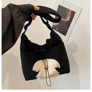 Detail of black corduroy tote bag featuring a cute plush dog patch and drawstring closure