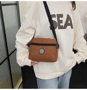 Brown nylon crossbody bag shown on model featuring adjustable strap and sport logo