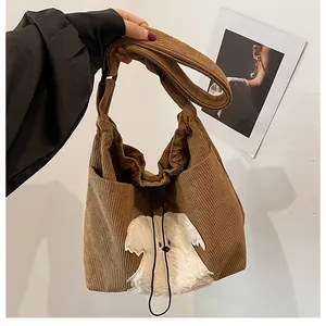 Detail of brown corduroy shoulder bag with cute white puppy patch and drawstring closure