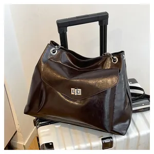 Macro view of polished brown leather tote bag showing silver metal swivel lock and texture