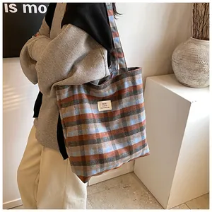 Dettaglio della grande borsa tote in tela a quadri con texture in lana e tracolla larga