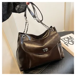 Detail of dark coffee PU leather tote showing metal twist lock and chain strap