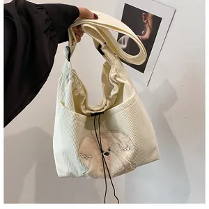 Detailed view of the corduroy tote bag with a cute puppy plush patch and wide strap