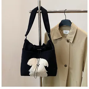 Detail of black corduroy shoulder bag featuring a white plush puppy patch embroidery