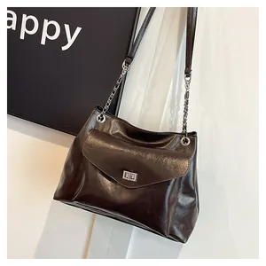 Detailed shot of dark brown oil-wax leather tote featuring silver twist-lock and chain strap