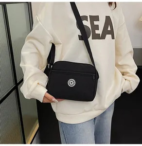 Close-up of black waterproof nylon crossbody bag with circular sport logo on model