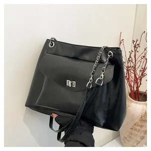 Detail of black faux leather tote bag showing silver chain strap and metal swivel lock