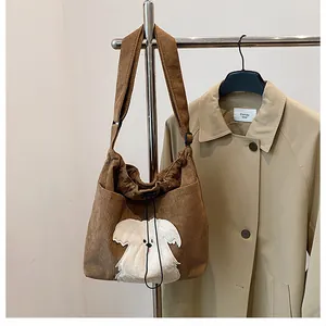 Detailed view of brown corduroy shoulder bag with cute white plush puppy patch