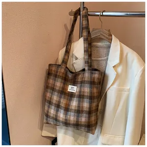 Vista dettagliata della borsa tote in tela a quadri appesa con un blazer bianco elegante