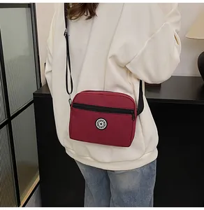 Macro shot of burgundy oxford crossbody bag featuring the sport logo and front zip pocket