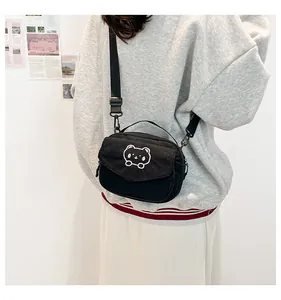 Détail du sac à bandoulière en velours côtelé noir avec broderie d'ours sur un mannequin