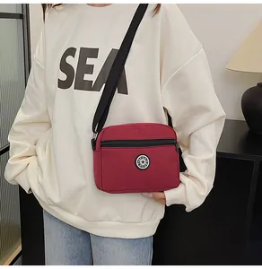 Red nylon crossbody bag with Sport logo and adjustable strap worn by a model