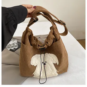 Detail of brown corduroy tote bag with cartoon dog patch and drawstring closure