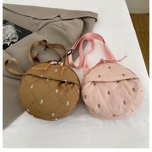 Close-up of quilted nylon round crossbody bag with delicate white bow embroidery