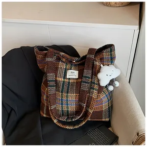 Dettaglio borsa shopper in lana a scacchi con ciondolo su sedia in tessuto