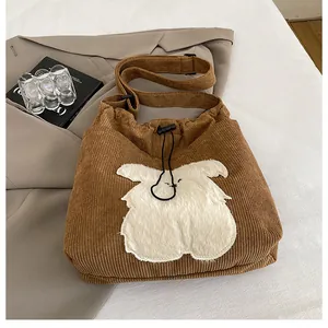 Detail of brown corduroy tote bag with soft animal patch and drawstring closure