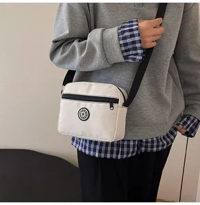 Detail of off-white oxford crossbody bag featuring SPORT logo and adjustable black strap
