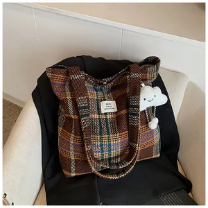 Dettaglio della grande borsa tote in lana a quadri con etichetta bianca e charm a nuvola