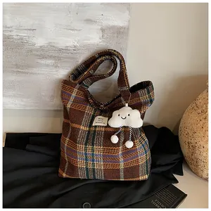 Dettaglio della borsa tote in lana scozzese con ciondolo a nuvola e etichetta logo