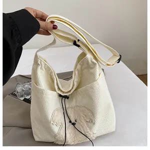 Detail of white corduroy tote bag with plush 3D dog embroidery and black strap