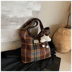 Dettaglio della borsa tote in tweed a quadretti con ciondolo a nuvola e tessuto retrò