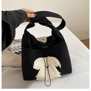 Close-up of black corduroy tote bag featuring a cute white plush puppy patch