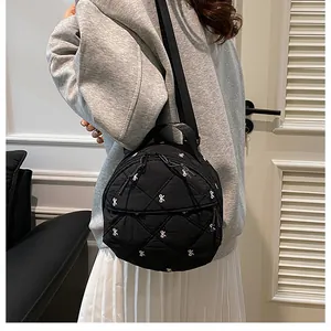Detail of quilted black nylon mini backpack with white bow embroidery and zip pockets