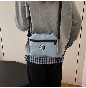 Detail view of a light blue nylon crossbody bag with an adjustable black shoulder strap