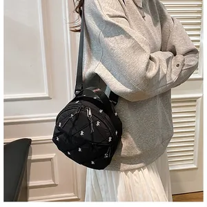 Detail of black quilted crossbody bag with white bow embroidery and multi-zipper design