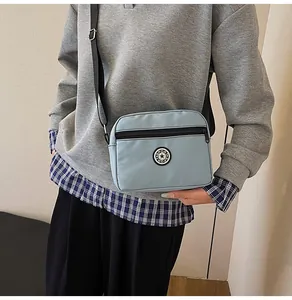 Detail of light blue nylon crossbody bag with sport logo and adjustable black strap