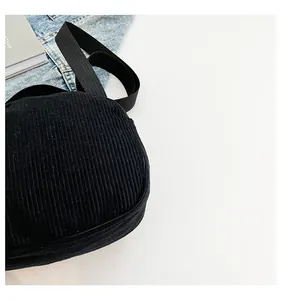 Détail de la texture d'un sac en velours côtelé noir avec bandoulière en tissu
